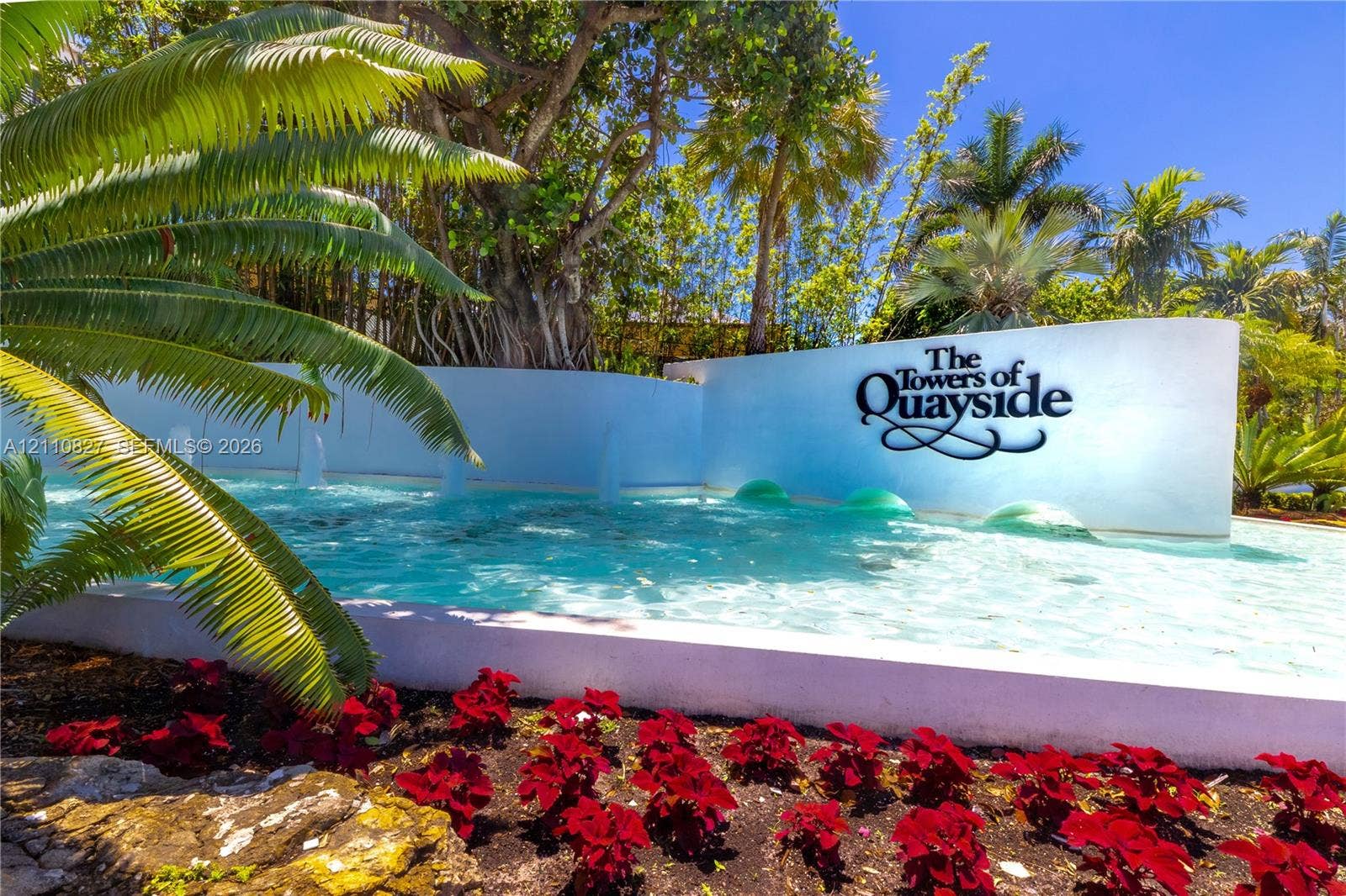 4000 Towerside Terrace, #908, Miami, Miami, FL 33138 Exterior entrance featuring a water fountain, white masonry retaining wall, mature palm trees, and landscaped floral beds