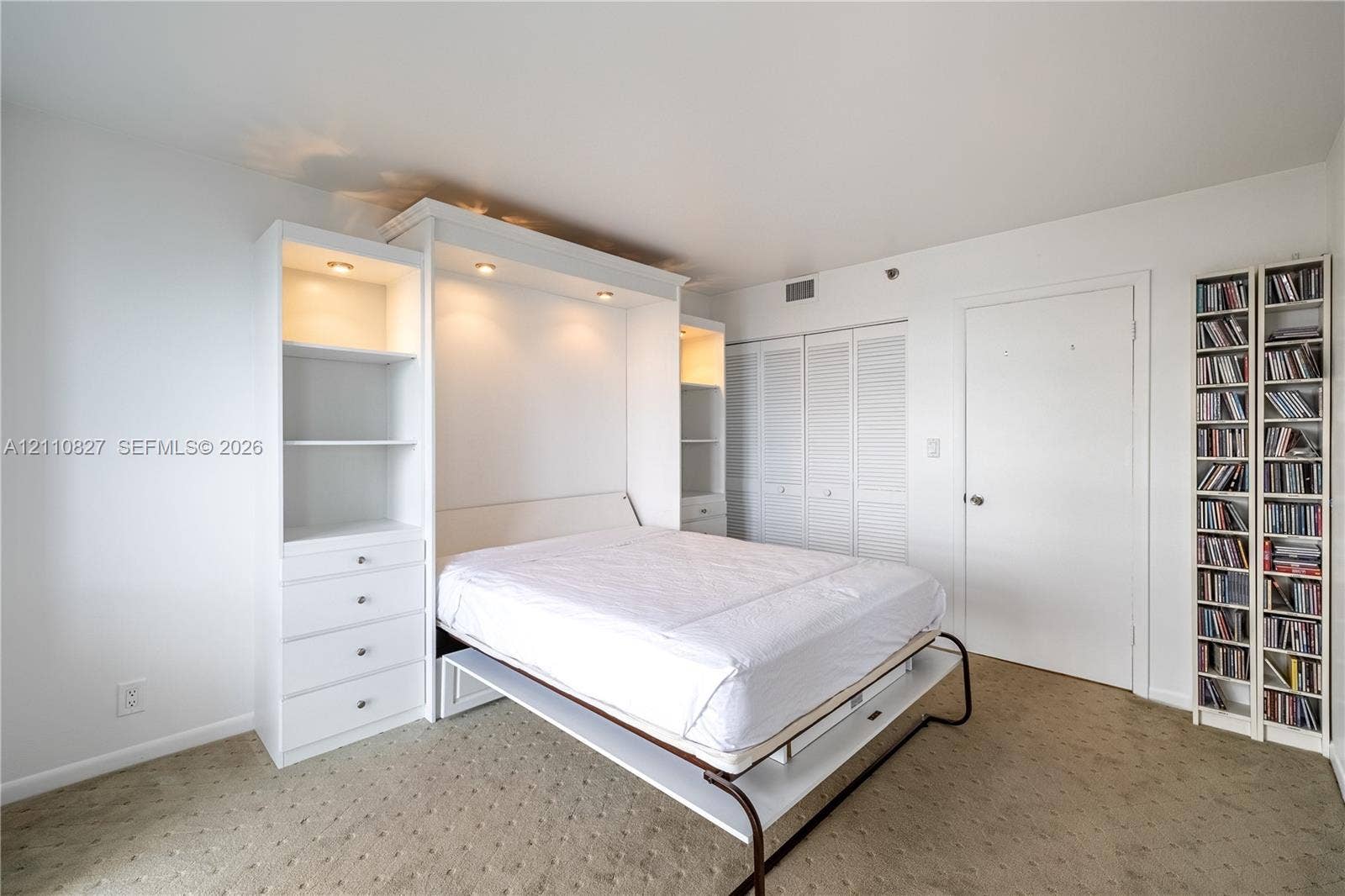 4000 Towerside Terrace, #908, Miami, Miami, FL 33138 Custom white built-in cabinetry featuring integrated recessed lighting, four drawers, and shelving, paired with white louvered closet doors and carpeted flooring
