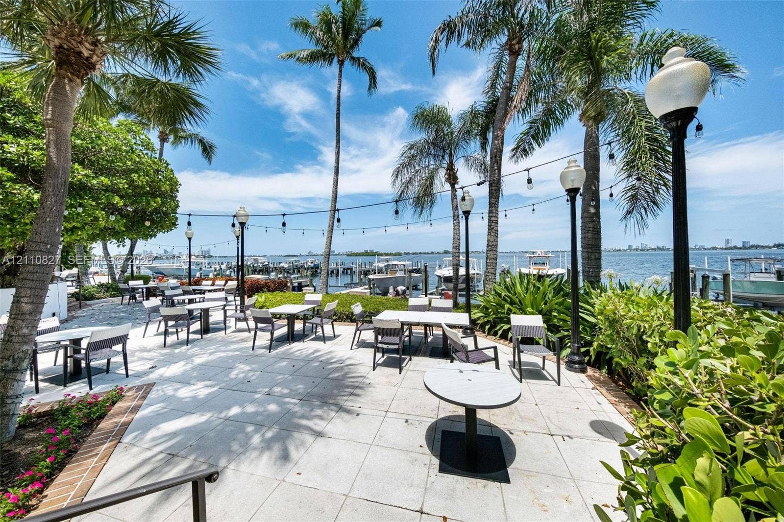 4000 Towerside Terrace, #908, Miami, Miami, FL 33138 Waterfront patio featuring stone paver flooring, mature palm trees, perimeter garden beds, and post-mounted lighting