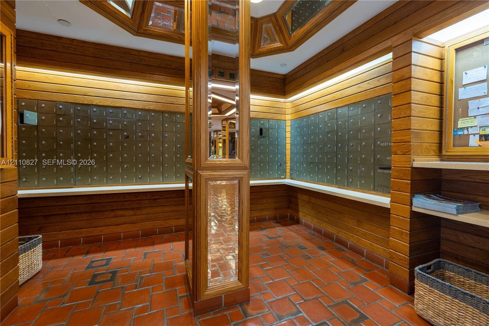 4000 Towerside Terrace, #908, Miami, Miami, FL 33138 Mailroom area featuring horizontal wood paneling, terracotta tile flooring, built-in metal mailboxes, integrated task lighting, and a central column with mirrored accents