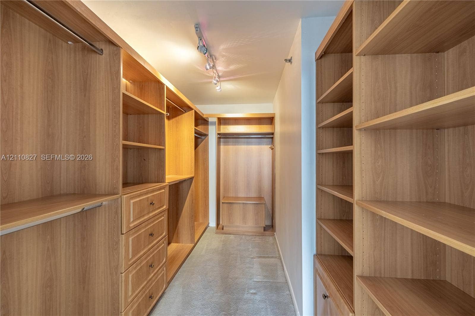 4000 Towerside Terrace, #908, Miami, Miami, FL 33138 Walk-in closet featuring extensive custom wood-finish shelving, integrated wardrobe hanging rods, a built-in drawer stack, a dedicated storage bench, and track lighting