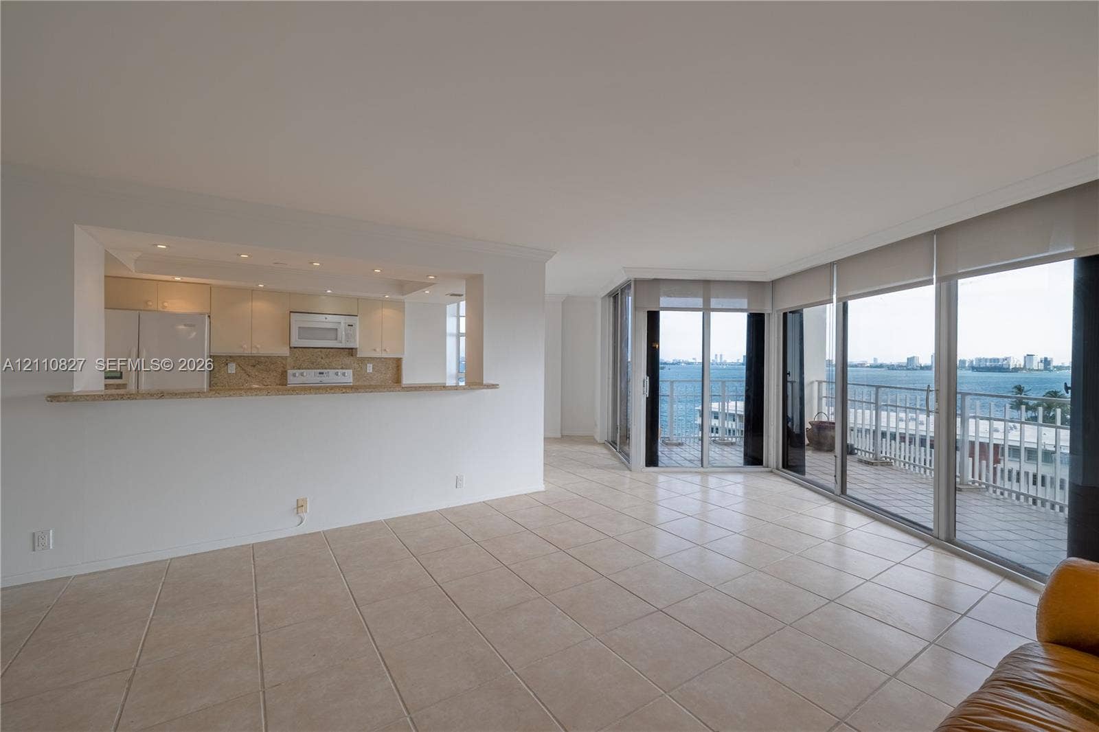 4000 Towerside Terrace, #908, Miami, Miami, FL 33138 Open-concept living space with tile flooring, pass-through kitchen counter, recessed lighting, and expansive floor-to-ceiling glass sliding doors leading to a balcony
