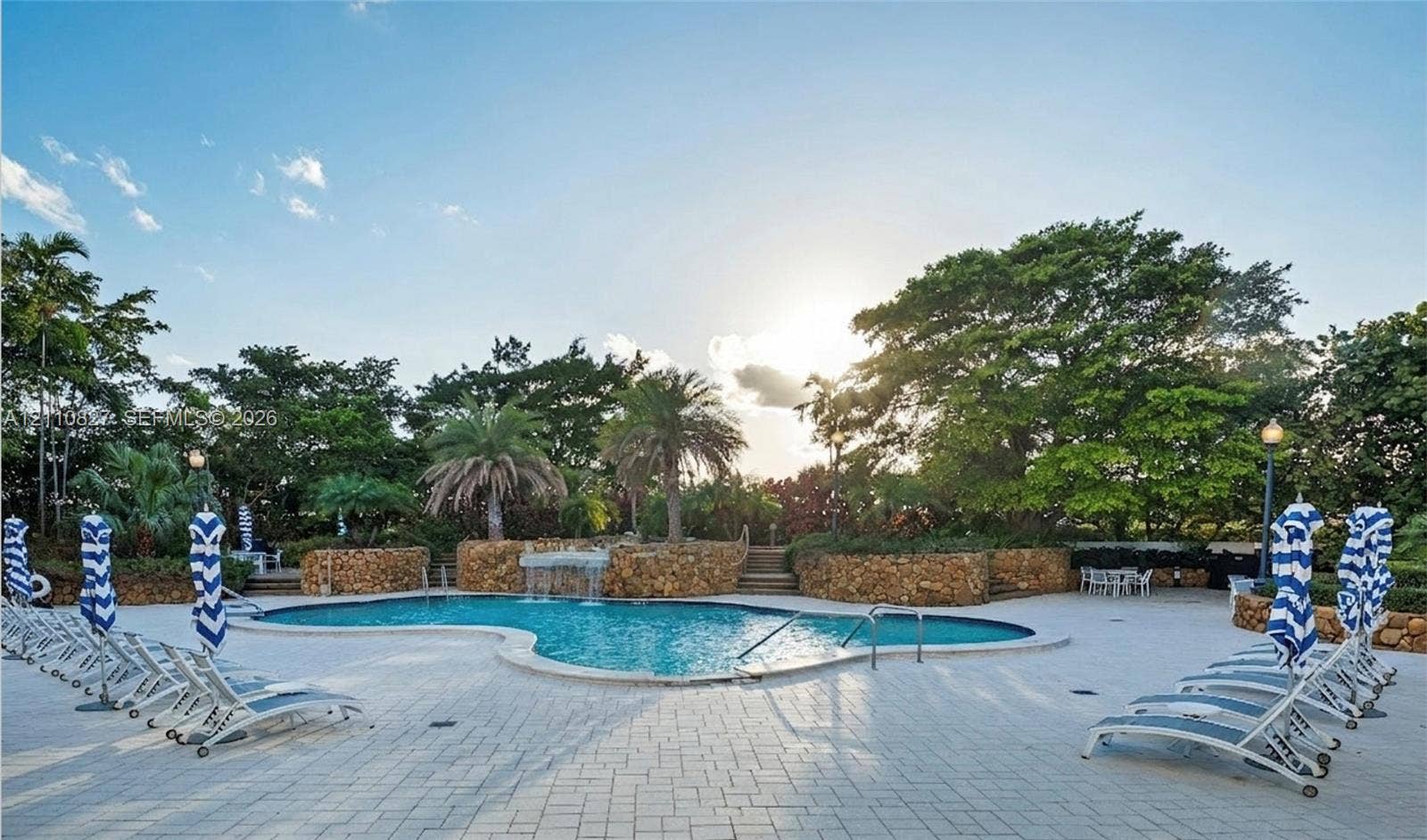 4000 Towerside Terrace, #908, Miami, Miami, FL 33138 Free-form swimming pool featuring a waterfall feature and stone masonry retaining walls, surrounded by a light-toned paver deck and mature landscaping