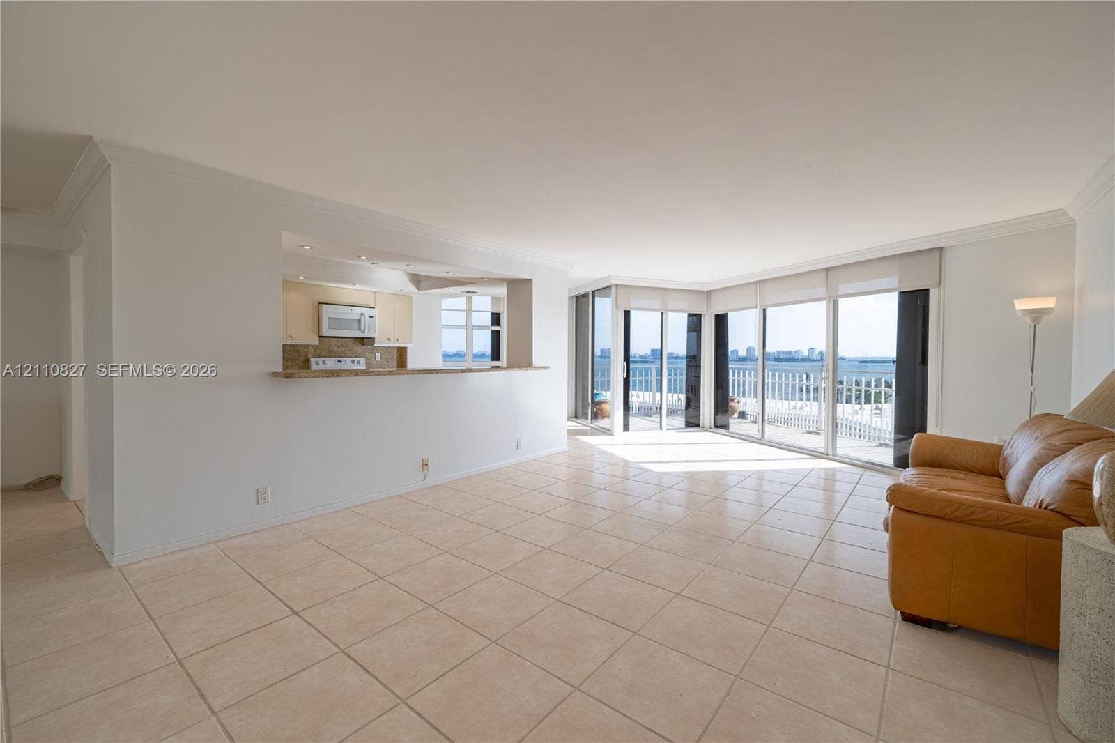 4000 Towerside Terrace, #908, Miami, Miami, FL 33138 Open-concept area featuring light-toned ceramic tile flooring, a pass-through kitchen counter, and floor-to-ceiling glass sliding doors leading to an exterior balcony