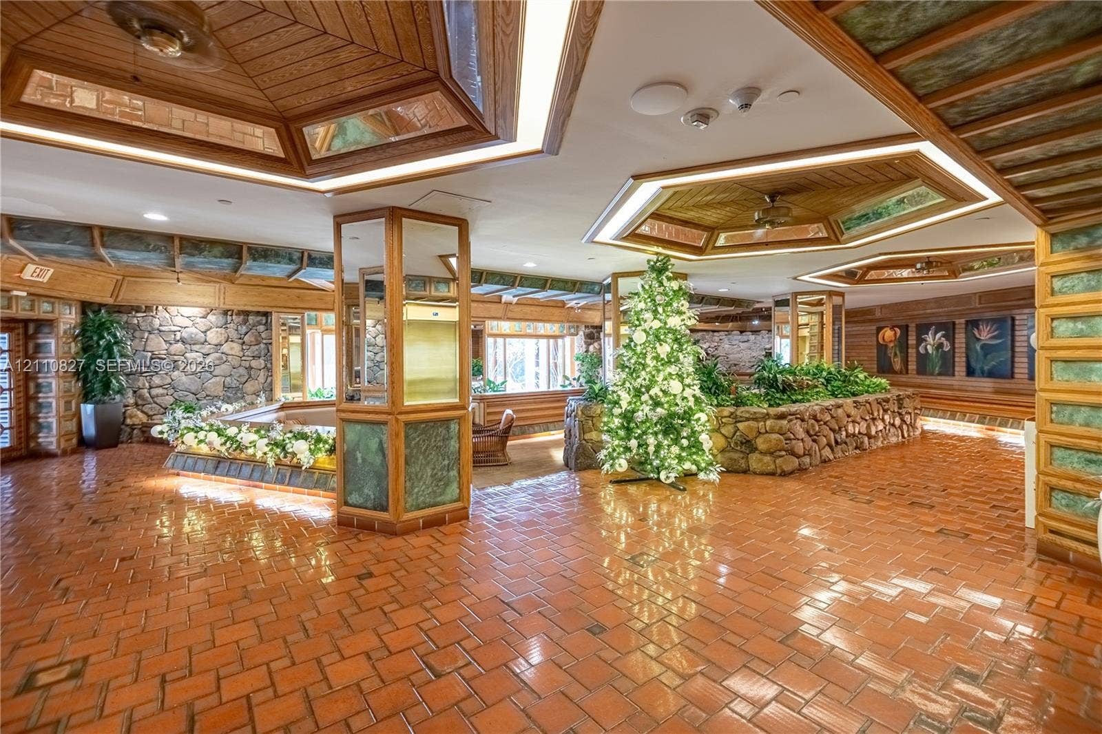4000 Towerside Terrace, #908, Miami, Miami, FL 33138 Spacious interior featuring terra-cotta tile flooring, wood-paneled tray ceilings with integrated lighting, custom stone accent walls, and mirrored support columns