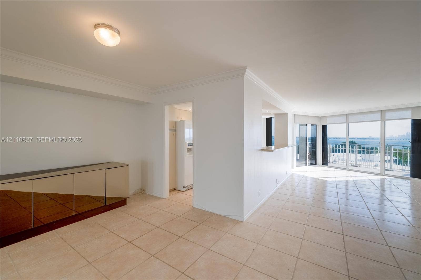 4000 Towerside Terrace, #908, Miami, Miami, FL 33138 Open floor plan featuring light-toned tile flooring, built-in mirrored cabinetry, a pass-through counter, and floor-to-ceiling windows