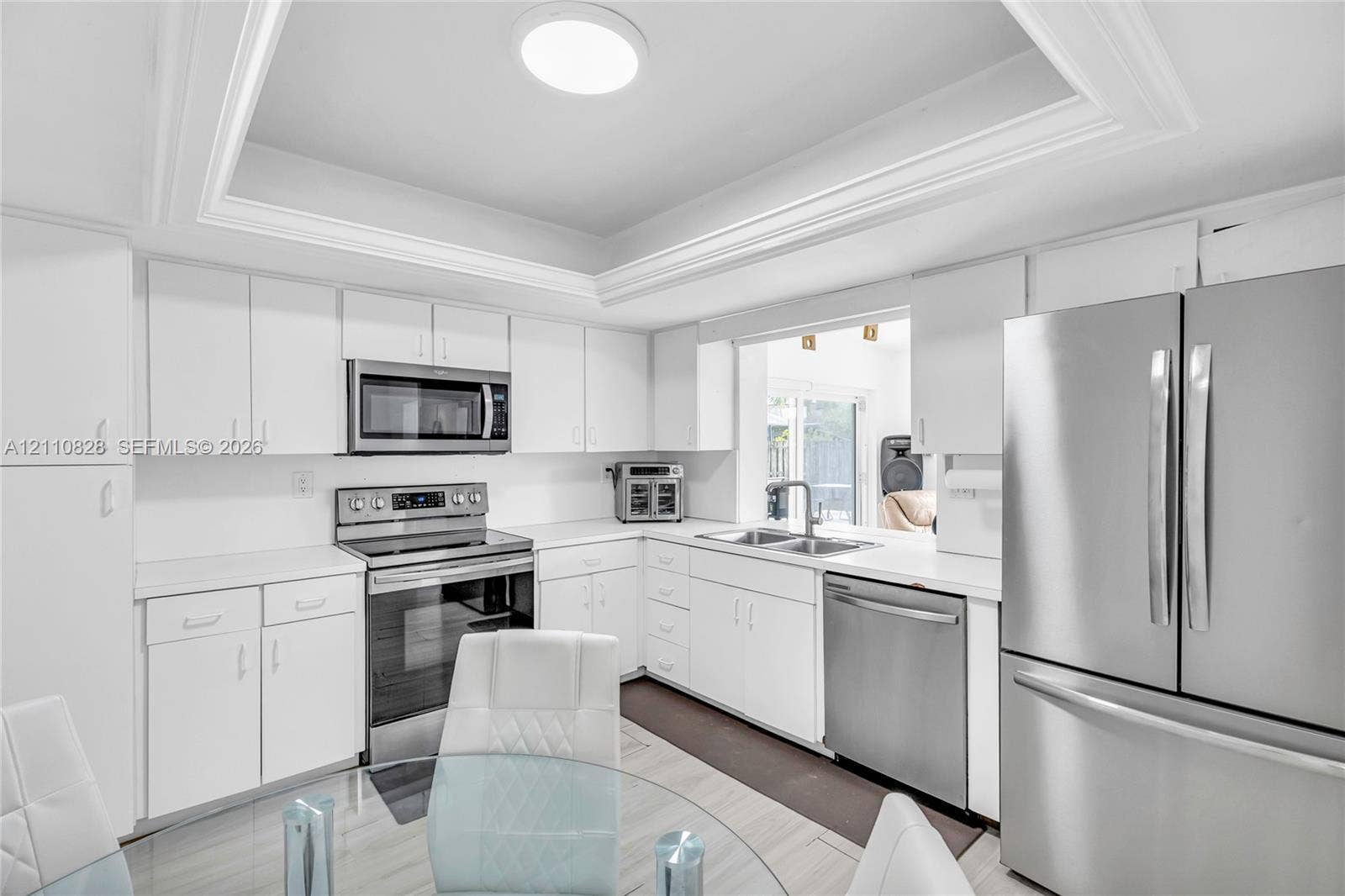 1600 NW 120th Avenue, Pembroke Pines, FL 33026 Kitchen featuring white shaker-style cabinetry, stainless steel appliances, a tray ceiling, and a dual-basin undermount sink with a gooseneck faucet