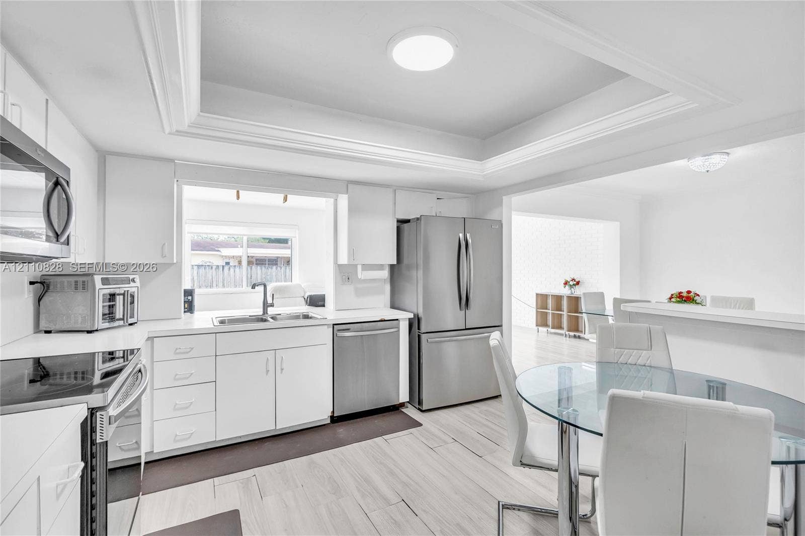 1600 NW 120th Avenue, Pembroke Pines, FL 33026 Kitchen featuring white cabinetry, stainless steel appliances, wood-finish flooring, and a tray ceiling