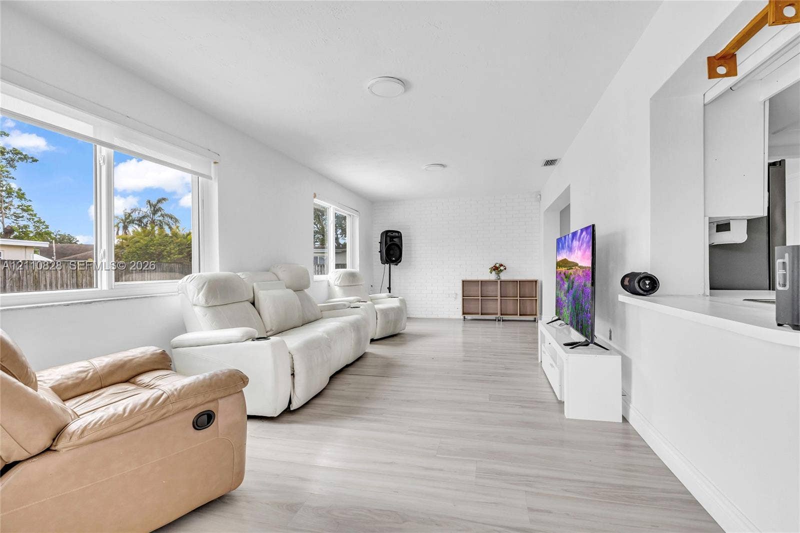 1600 NW 120th Avenue, Pembroke Pines, FL 33026 Interior living space featuring wood-finish flooring, a white painted brick accent wall, and expansive windows