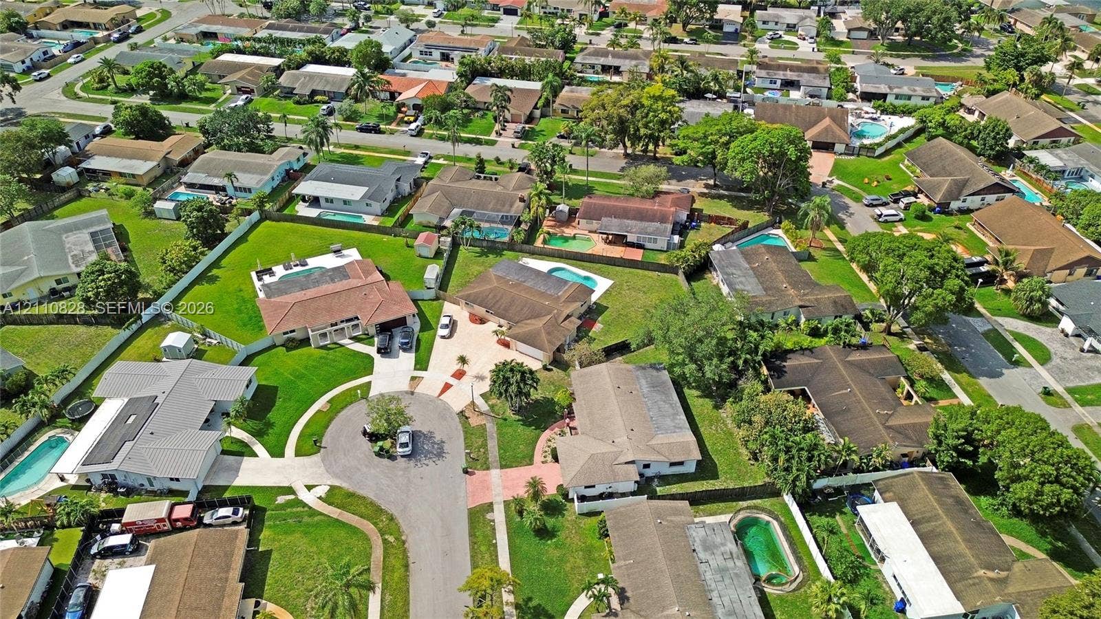 1600 NW 120th Avenue, Pembroke Pines, FL 33026 Aerial perspective of a suburban neighborhood characterized by varied residential architectural styles, intersecting paved streets, established mature tree canopy, and green spaces