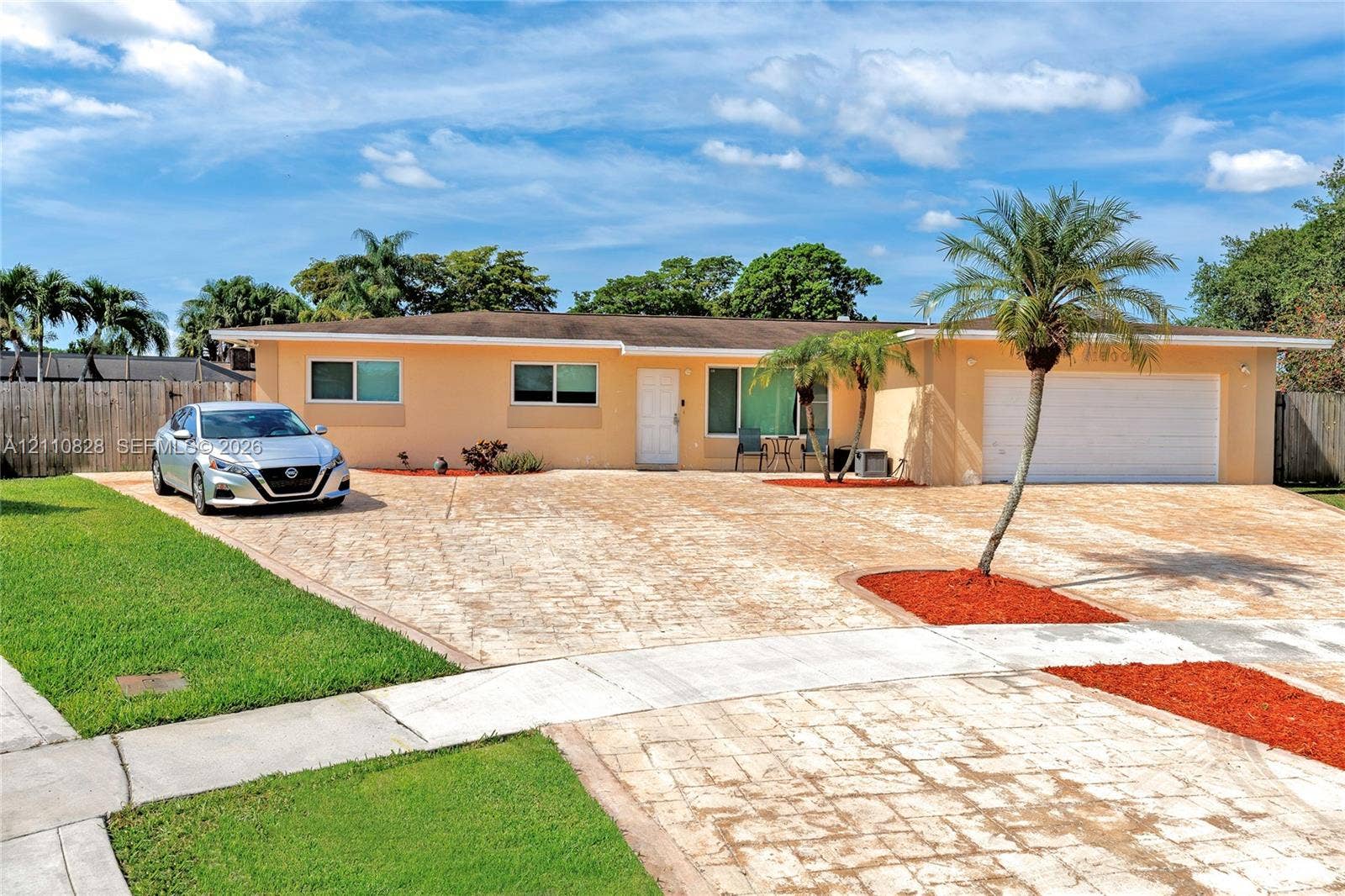 1600 NW 120th Avenue, Pembroke Pines, FL 33026 Single-story residence featuring a stamped concrete driveway, two-car garage, manicured lawn, and mature palm landscaping