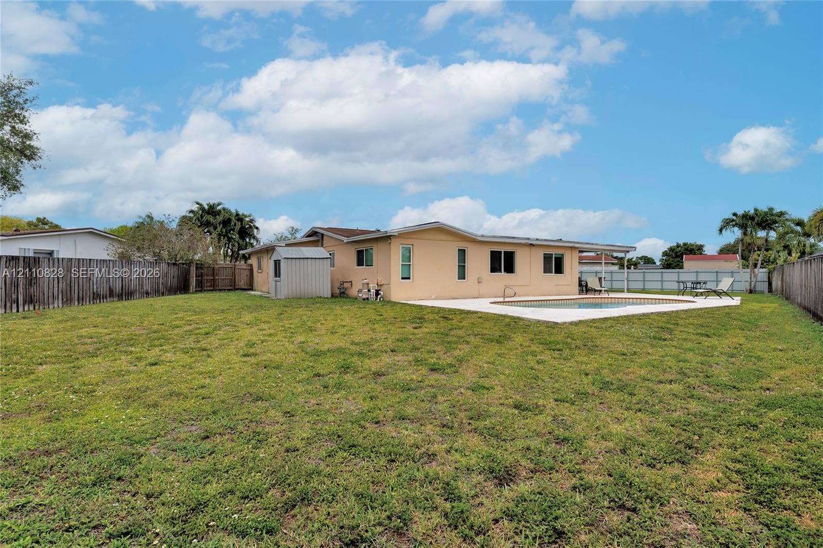 1600 NW 120th Avenue, Pembroke Pines, FL 33026 Expansive backyard featuring a concrete patio, in-ground swimming pool, storage shed, and perimeter wood fencing