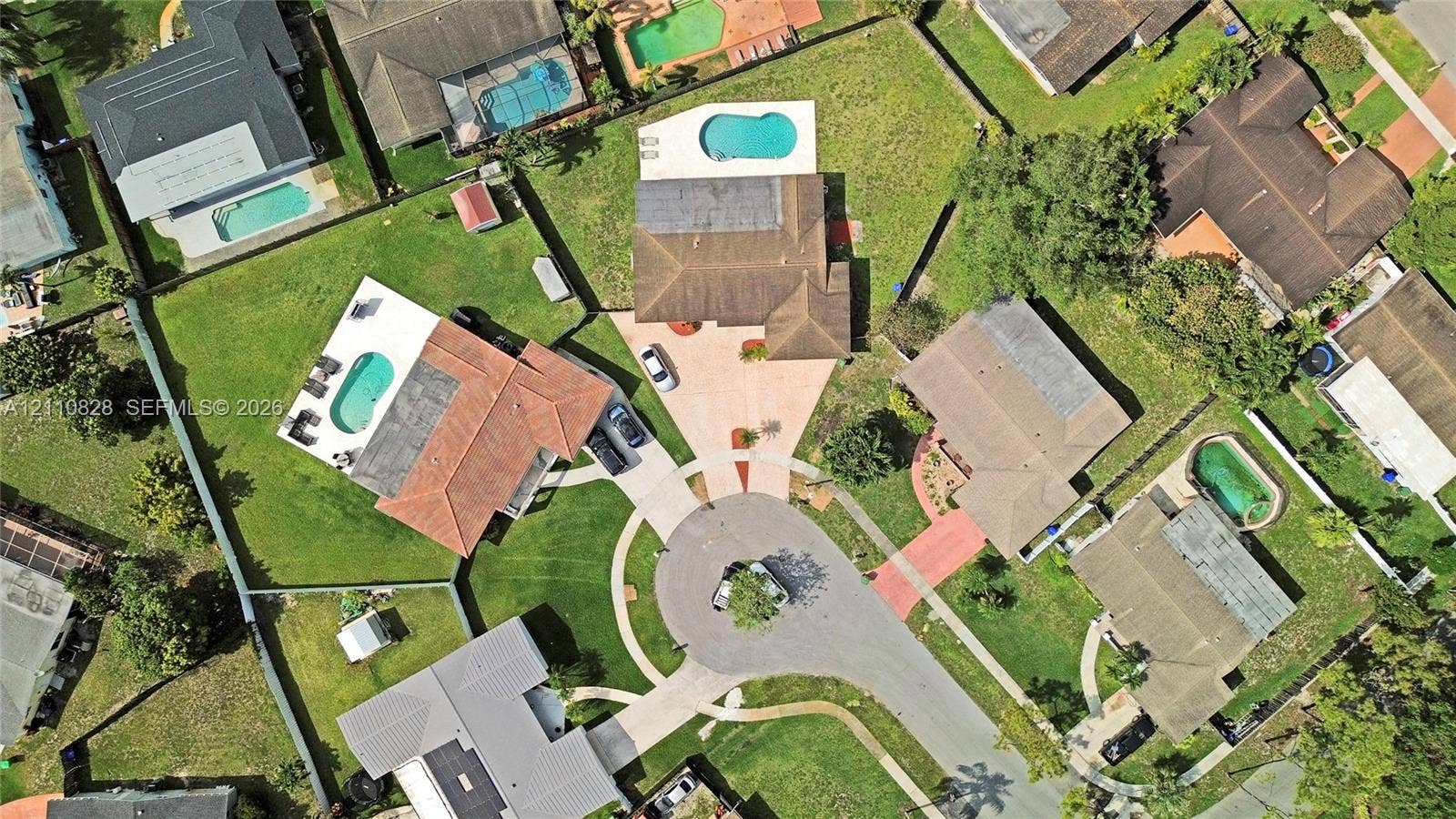 1600 NW 120th Avenue, Pembroke Pines, FL 33026 Aerial perspective of the property featuring a rectangular in-ground swimming pool, concrete paved driveway, shingle roofing, and established lawn area