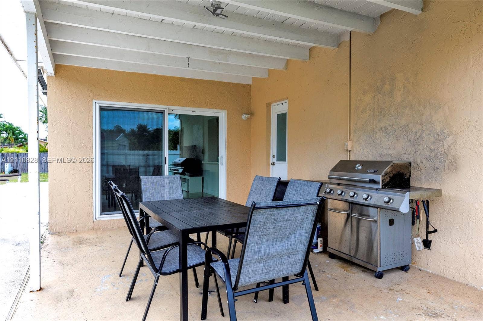 1600 NW 120th Avenue, Pembroke Pines, FL 33026 Covered patio featuring a concrete floor, exposed ceiling joists, sliding glass door, and a built-in metal outdoor grill