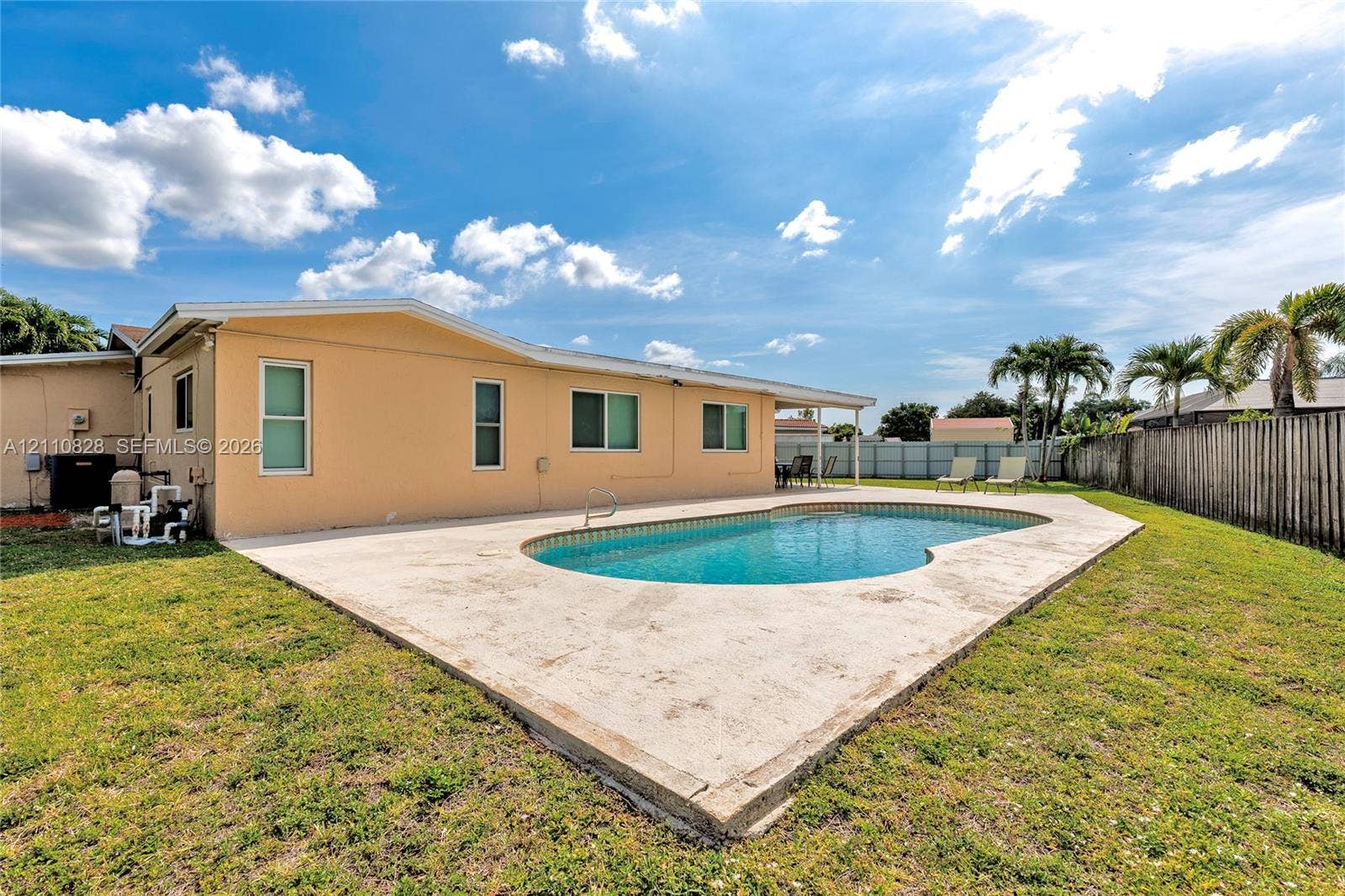 1600 NW 120th Avenue, Pembroke Pines, FL 33026 In-ground swimming pool with a concrete patio, stucco exterior siding, and perimeter wood fencing