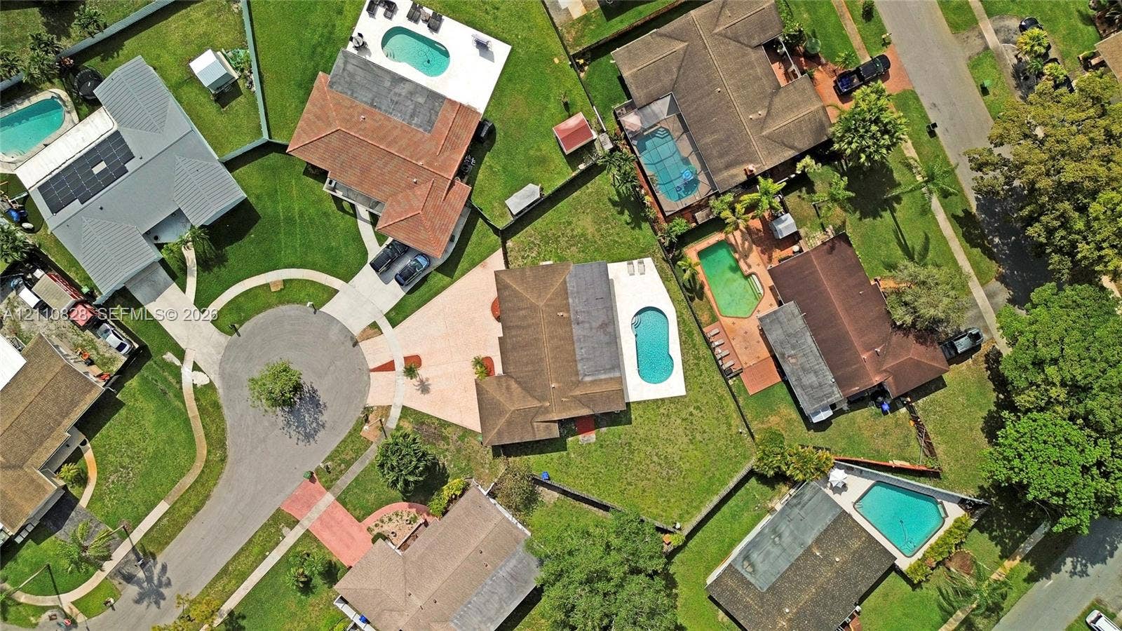 1600 NW 120th Avenue, Pembroke Pines, FL 33026 Aerial perspective of a cul-de-sac residential property featuring a multi-hipped roofline, private swimming pool, concrete patio, and established lawn