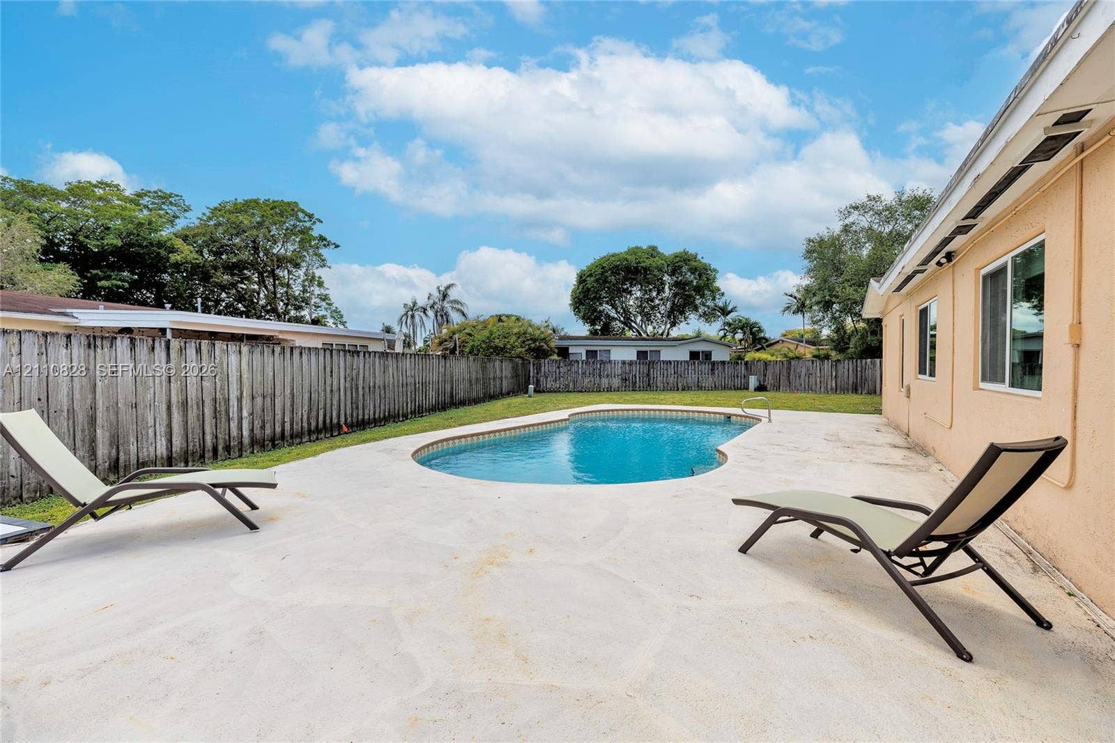 1600 NW 120th Avenue, Pembroke Pines, FL 33026 Backyard featuring an in-ground swimming pool, concrete patio, perimeter wood fencing, and a grass lawn