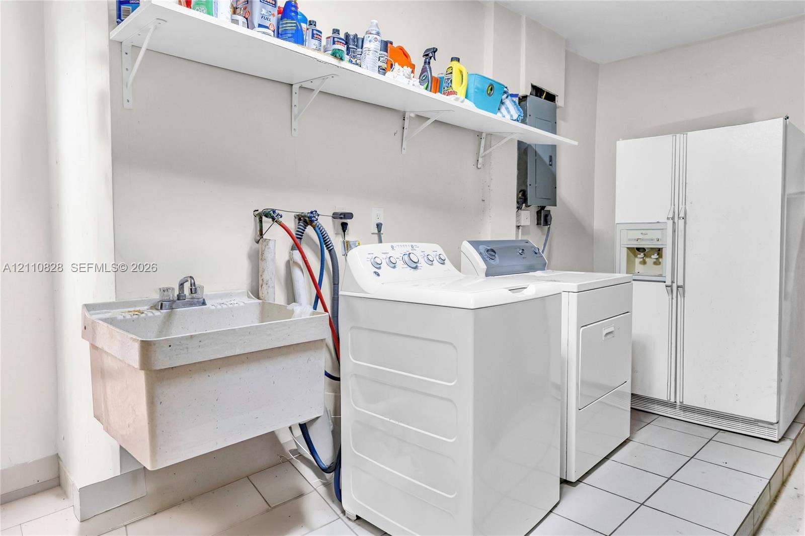 1600 NW 120th Avenue, Pembroke Pines, FL 33026 Utility space featuring tile flooring, a wall-mounted utility sink with metal faucet, and built-in open shelving