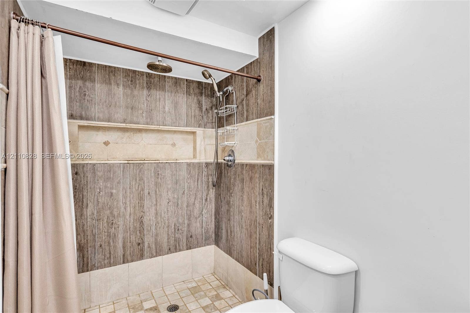 1600 NW 120th Avenue, Pembroke Pines, FL 33026 Shower featuring wood-finish wall tile, integrated tile recessed shelving, stone-composite floor tile, and a multi-function shower head system