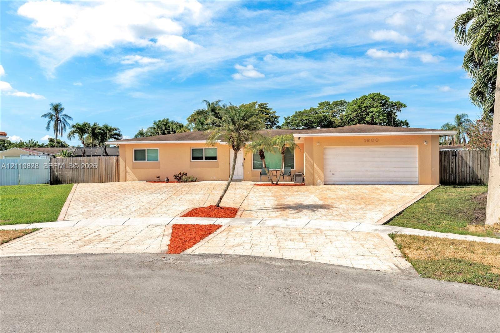 1600 NW 120th Avenue, Pembroke Pines, FL 33026 Single-story residence featuring a textured paved driveway, attached two-car garage, and neutral exterior finish