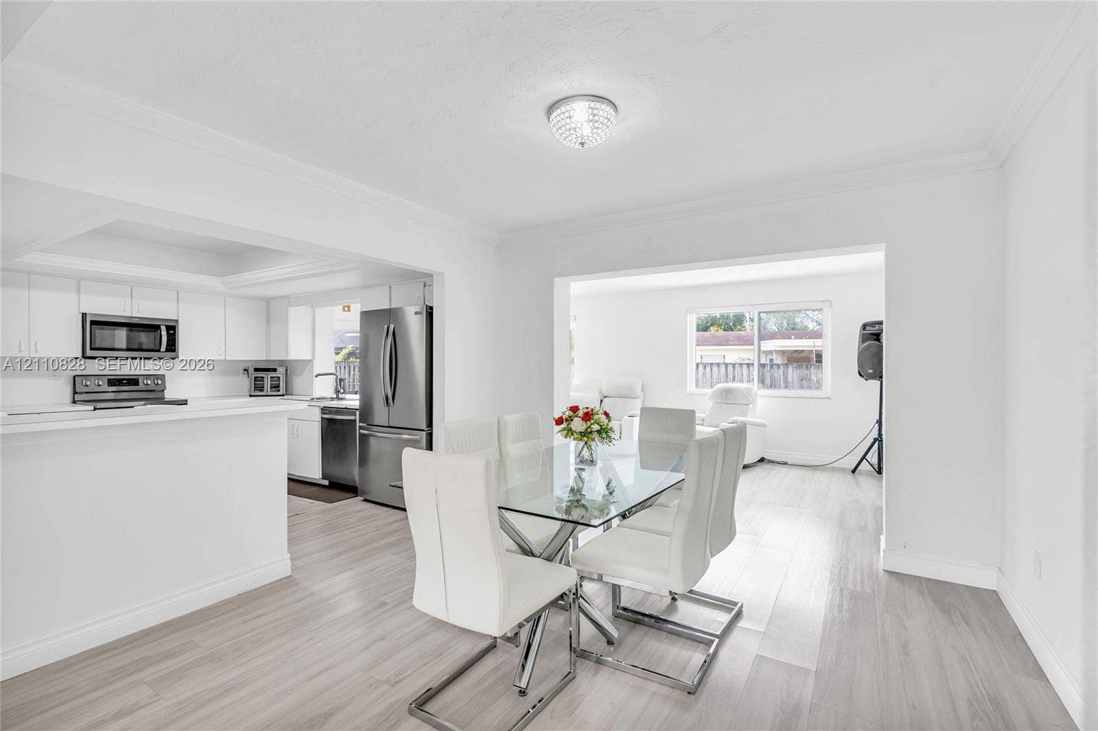 1600 NW 120th Avenue, Pembroke Pines, FL 33026 Open-concept space featuring wood-finish flooring, white cabinetry, stainless steel appliances, recessed tray ceiling, and a crystal-style flush-mount light fixture