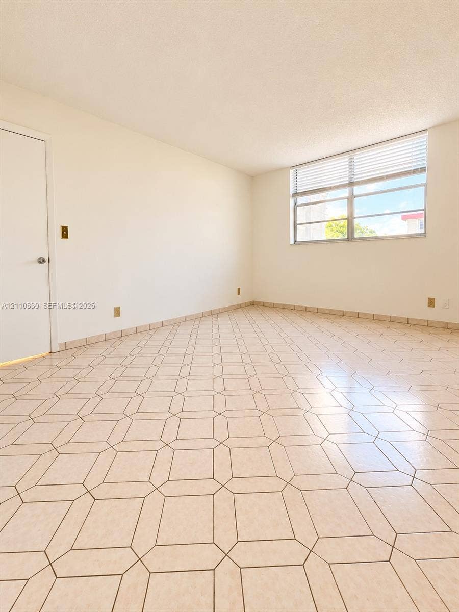 Neutral-toned geometric tile flooring and expansive single-pane window featuring horizontal blinds