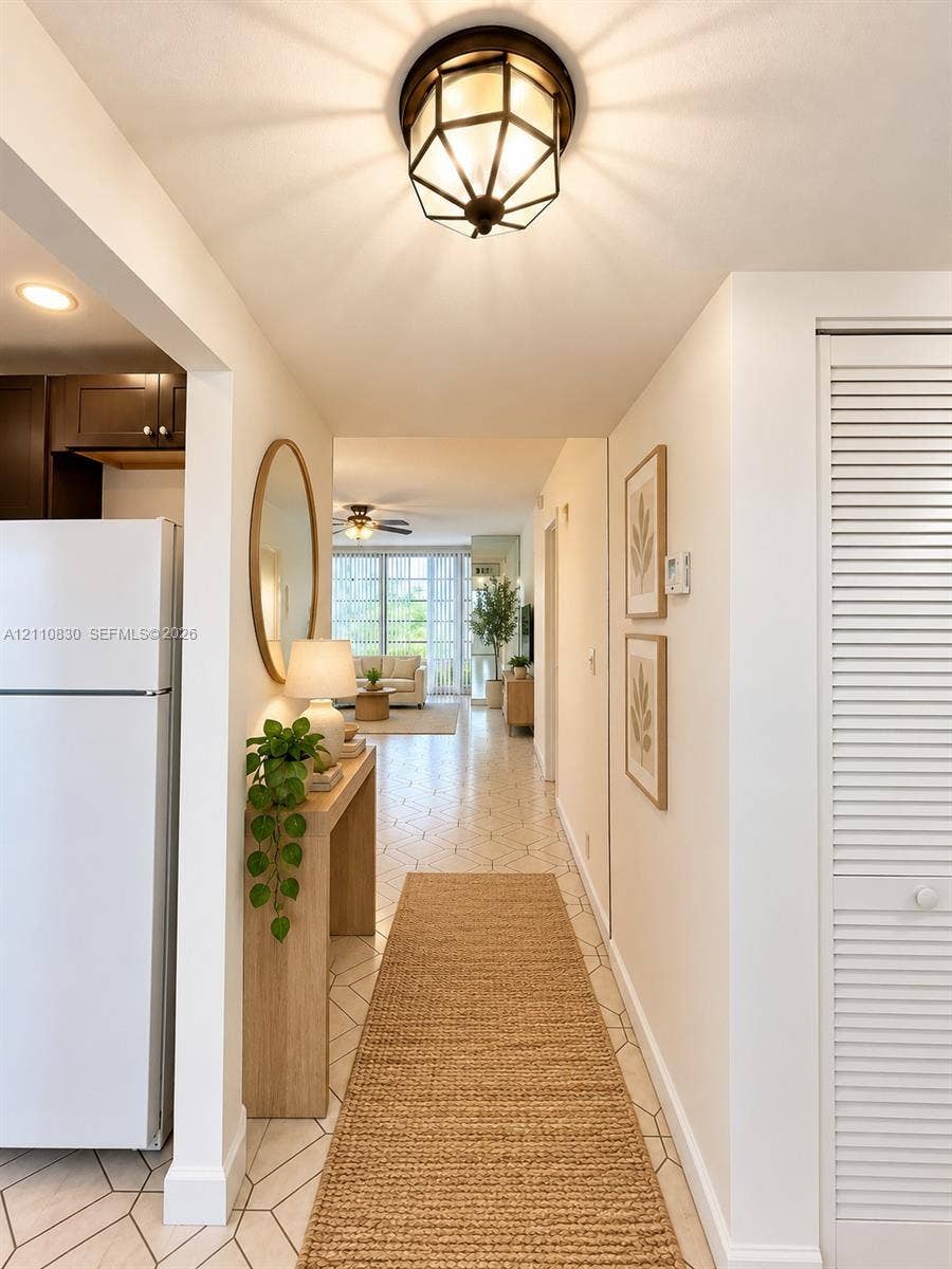 STAGED Hallway featuring geometric tile flooring, a multi-faceted flush-mount light fixture, and floor-to-ceiling louvered closet doors