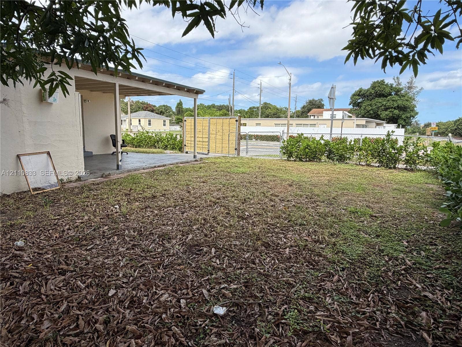 Backyard featuring a covered concrete patio, ground-level sod, and wood-paneled privacy fencing
