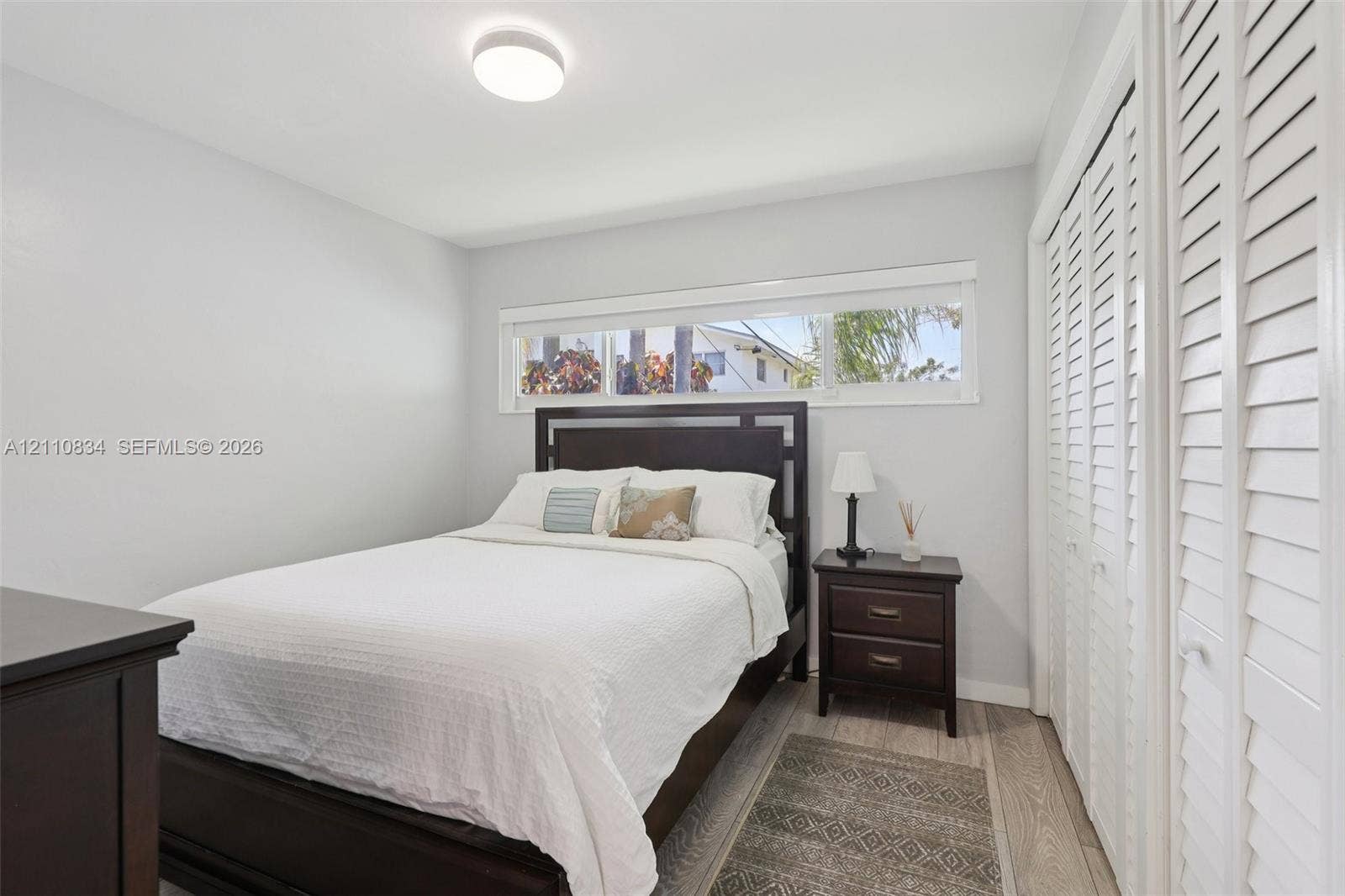 4120 SW 15th Street, Miami, FL 33142 Neutral wall tones, wood-finish flooring, horizontal window, and floor-to-ceiling closet with louvered doors
