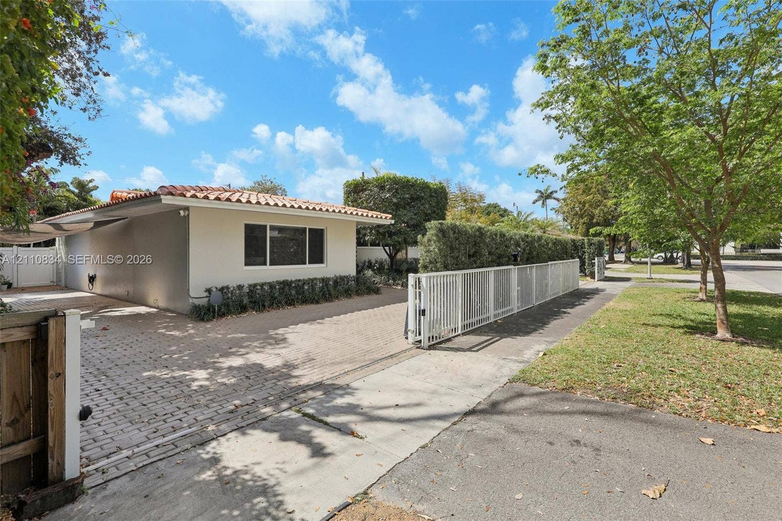 4120 SW 15th Street, Miami, FL 33142 Single-story exterior featuring a clay tile roof, paved driveway, and perimeter white metal fencing