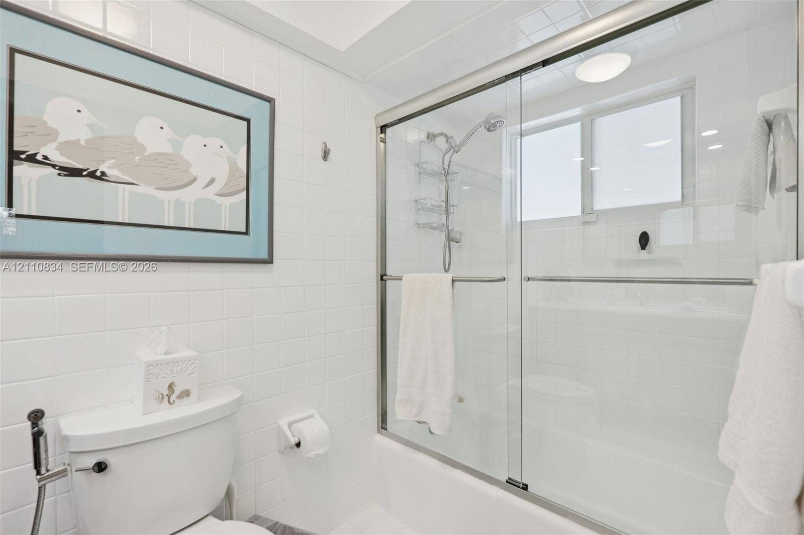 4120 SW 15th Street, Miami, FL 33142 Bathroom featuring white tile wall surround, glass-enclosed shower-tub combination, chrome plumbing fixtures, and a recessed ceiling light