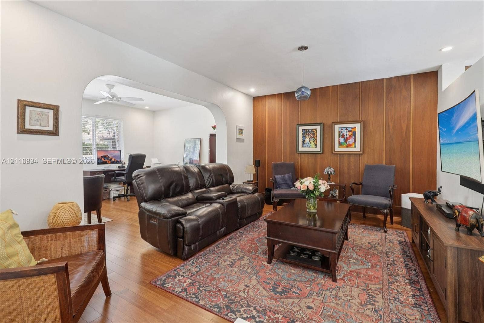 4120 SW 15th Street, Miami, FL 33142 Living area featuring wood-finish flooring, a wood-paneled accent wall, a distinctive arched architectural opening, and recessed lighting