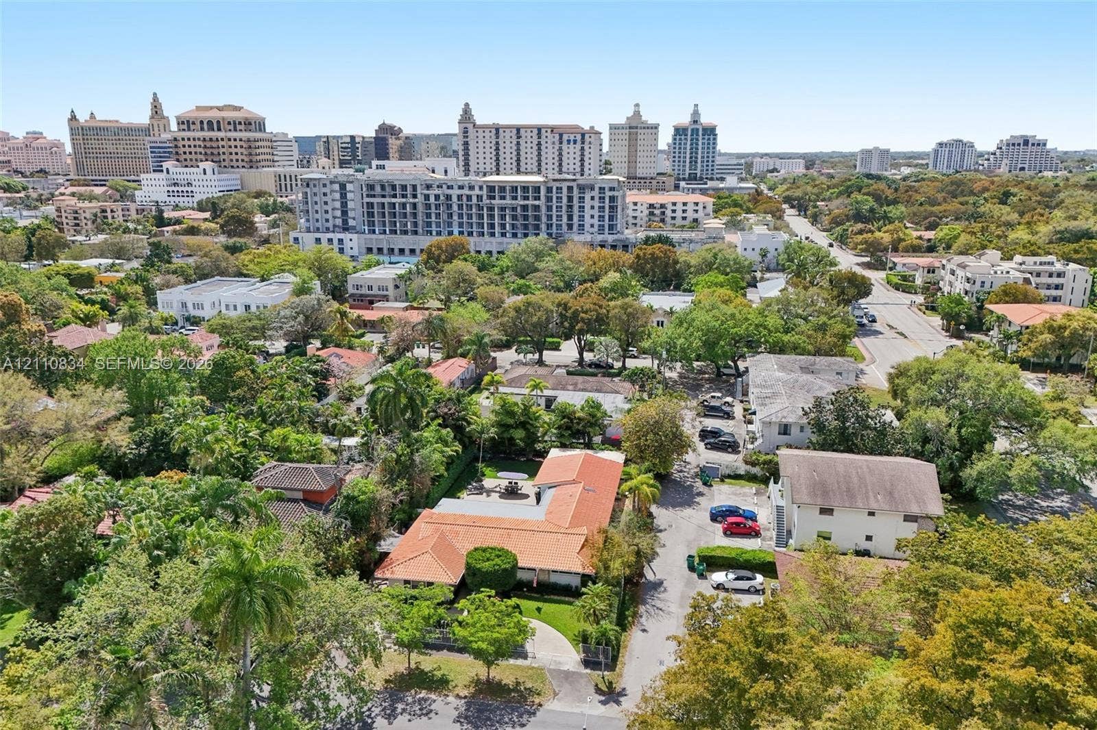4120 SW 15th Street, Miami, FL 33142 Aerial perspective of a single-story residence featuring a red clay tile roof, a paved driveway, and mature landscaping