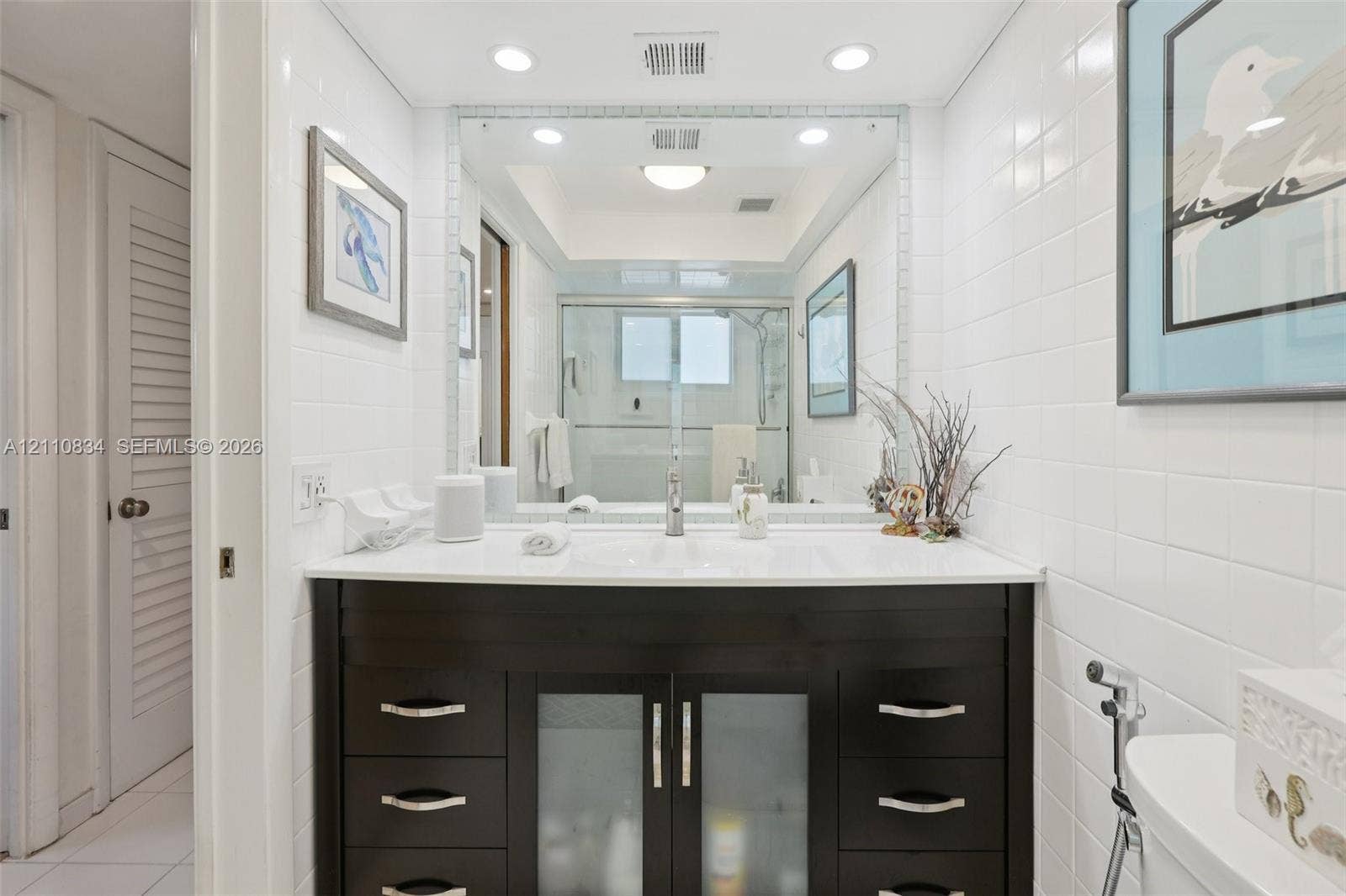 4120 SW 15th Street, Miami, FL 33142 Bathroom featuring a dark wood-finish vanity with an integrated basin, white solid-surface countertop, recessed lighting, and a floor-to-ceiling mirror with a tiled border