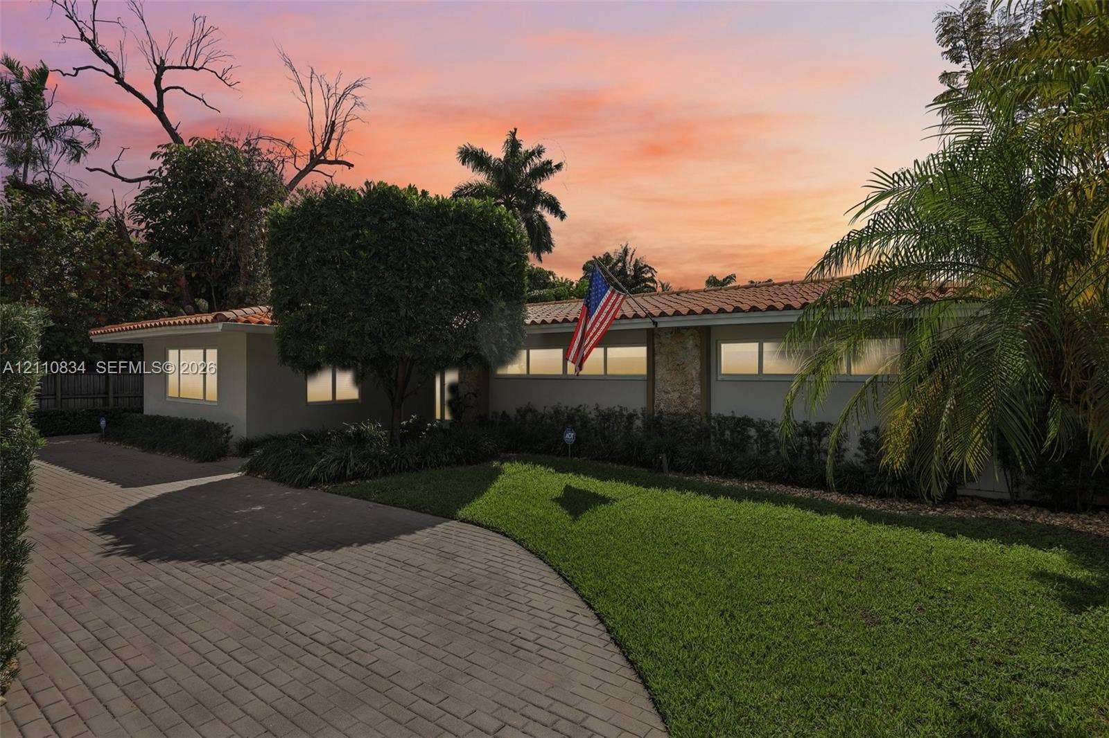 4120 SW 15th Street, Miami, FL 33142 Single-story residence featuring a clay tile roof, stone masonry accents, a paved driveway, and manicured landscaping
