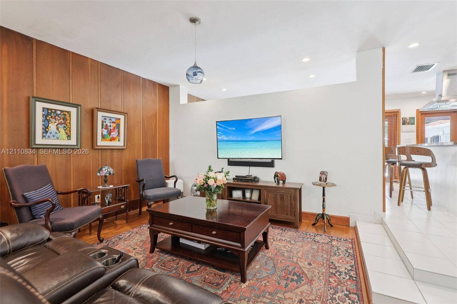 4120 SW 15th Street, Miami, FL 33142 Wood-paneled accent wall, recessed lighting, glass pendant fixture, hardwood flooring, and tiered floor elevation