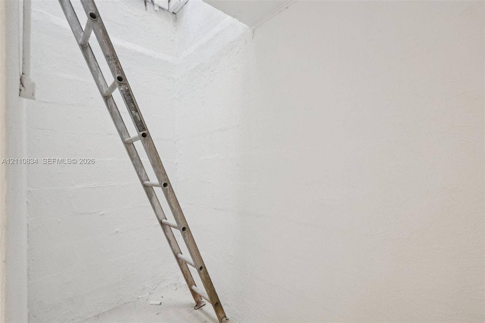 4120 SW 15th Street, Miami, FL 33142 Enclosed storage area featuring painted masonry block walls and a fixed metal access ladder
