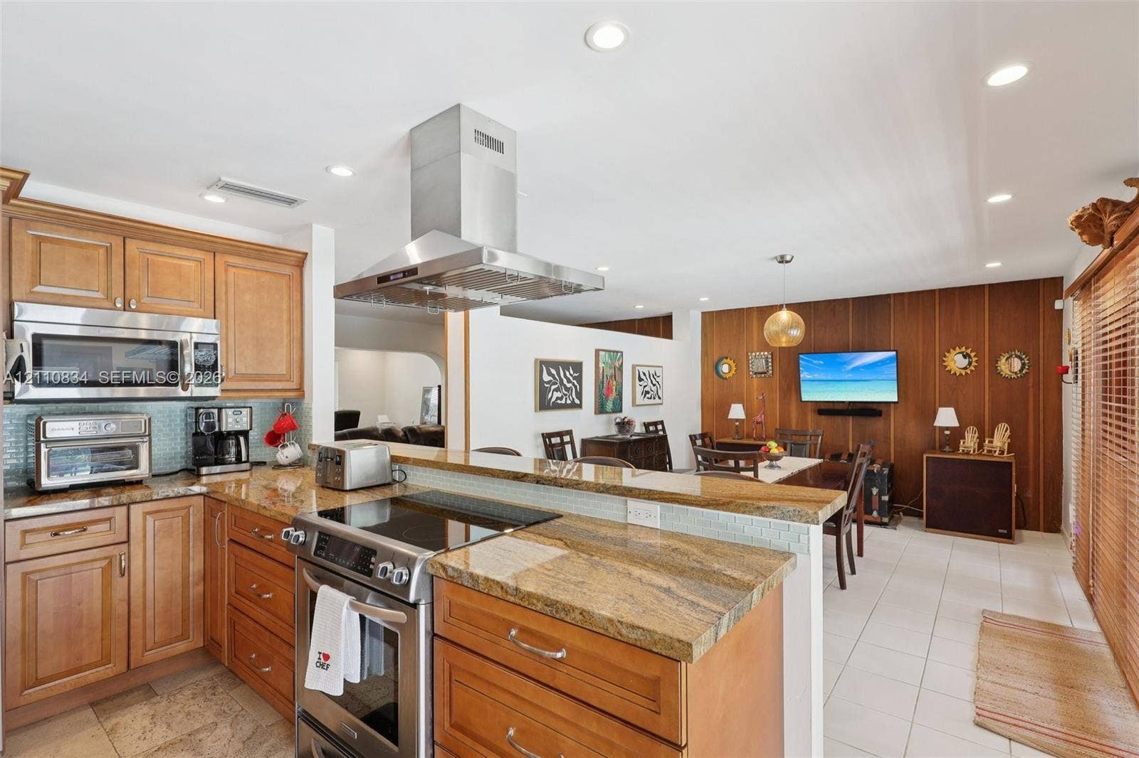 4120 SW 15th Street, Miami, FL 33142 Kitchen featuring wood cabinetry, stone countertops, stainless steel range with overhead vent hood, built-in microwave, and tile flooring