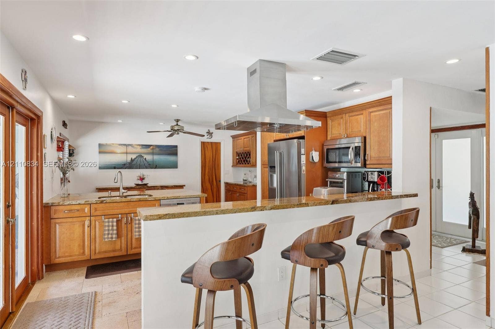 4120 SW 15th Street, Miami, FL 33142 Kitchen featuring wood cabinetry, stone countertops, a raised breakfast bar, a stainless steel chimney-style range hood, and tile flooring