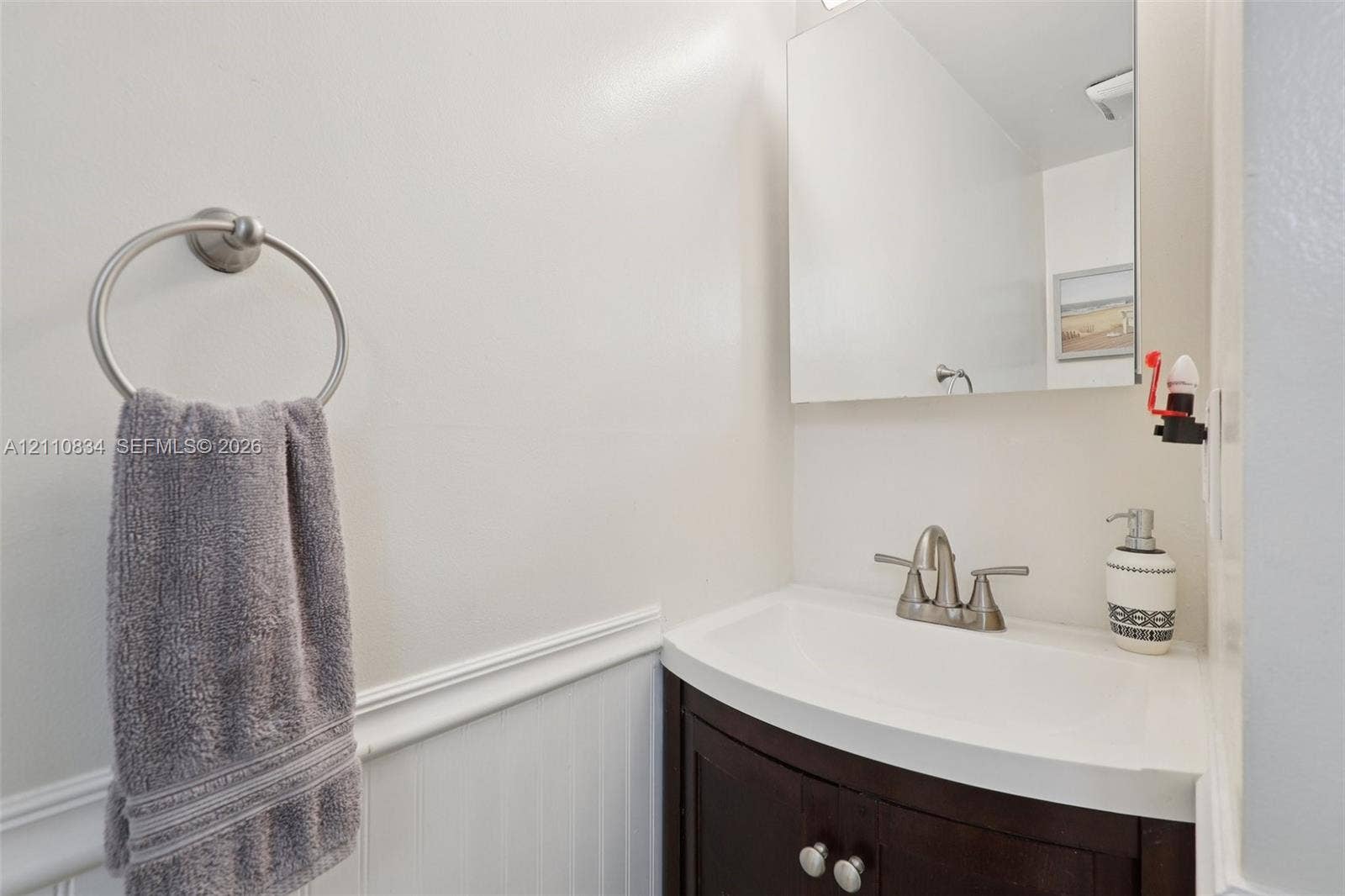 4120 SW 15th Street, Miami, FL 33142 Dark wood-finish vanity with integrated sink, brushed nickel faucet, wall-mounted mirror, and white wainscoting