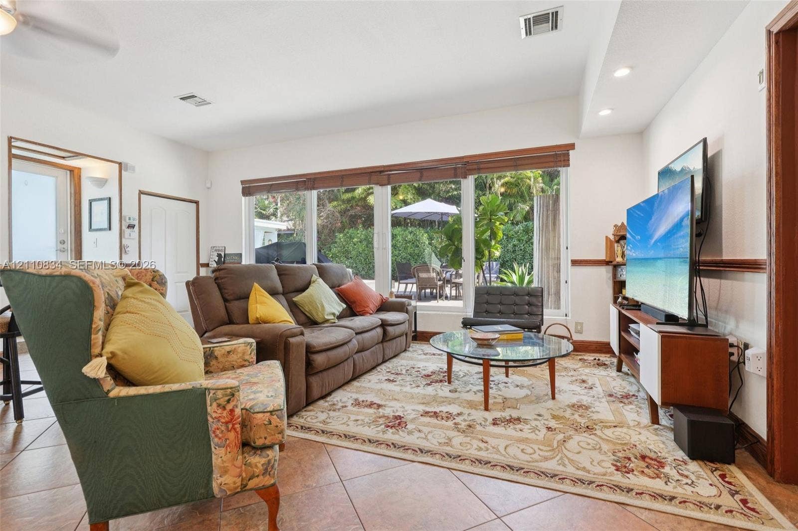 4120 SW 15th Street, Miami, FL 33142 Living area featuring large-format ceramic tile flooring, recessed lighting, and a panoramic window wall with wood-slat blinds