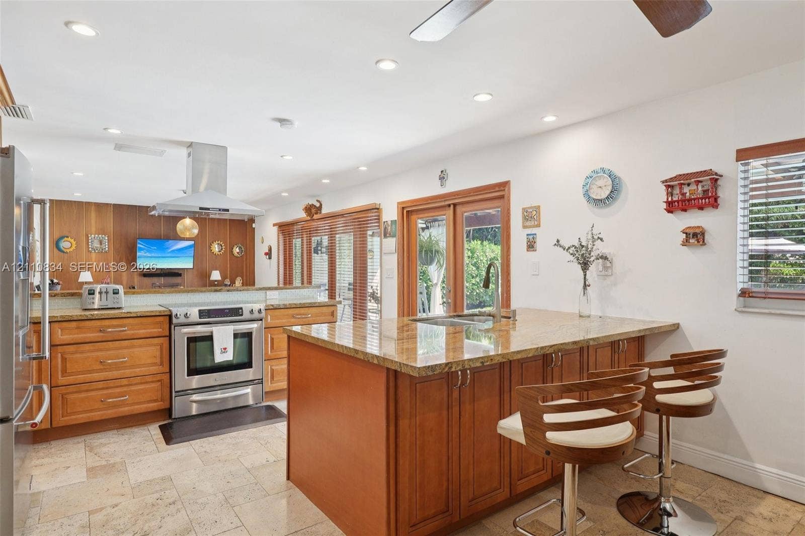 4120 SW 15th Street, Miami, FL 33142 Kitchen featuring wood cabinetry, stone countertops, a center island with an integrated sink, stainless steel appliances, and stone-tile flooring