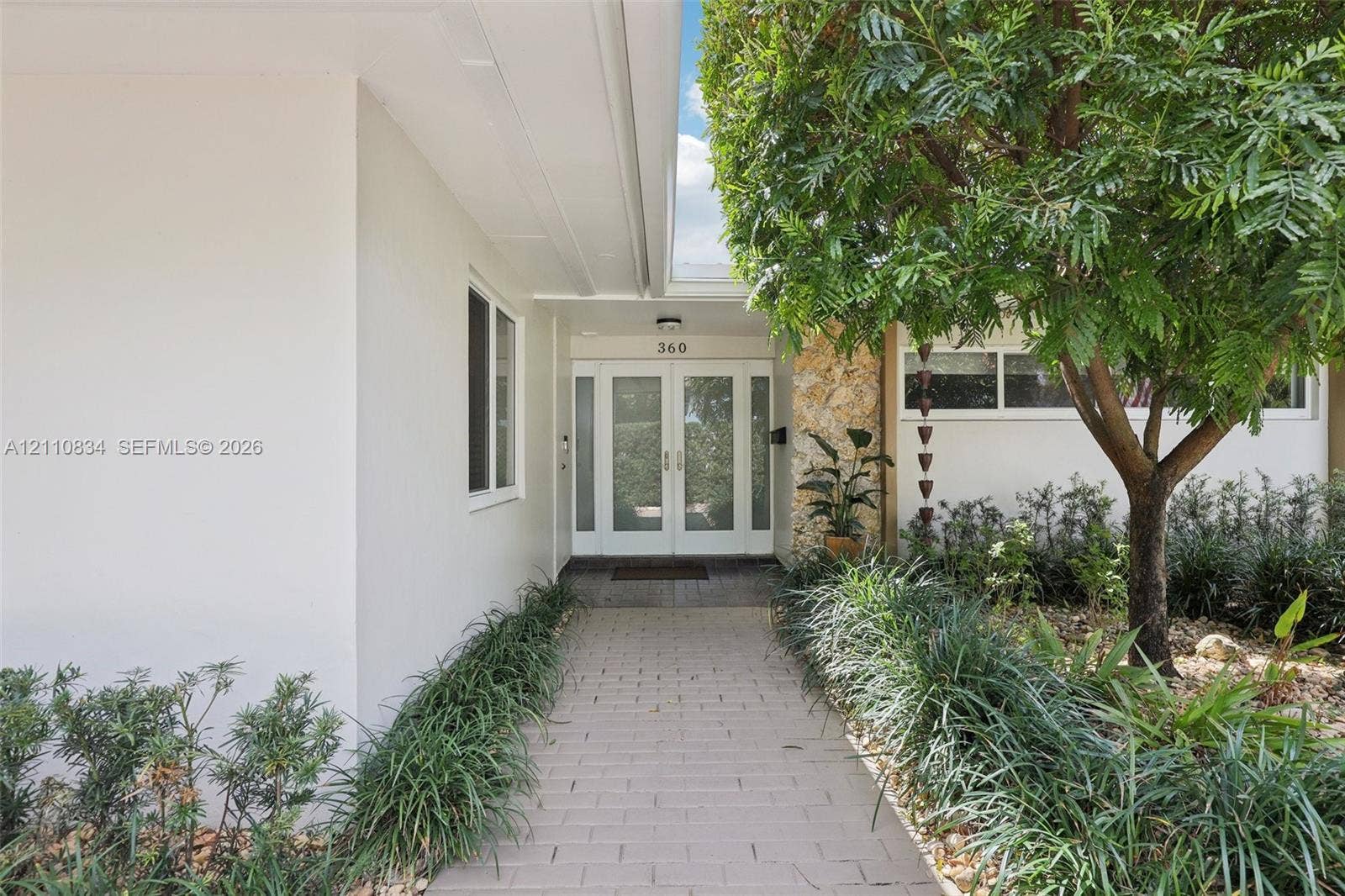 4120 SW 15th Street, Miami, FL 33142 Covered entrance featuring double glass-paneled doors, stone-accented exterior wall, and paver walkway