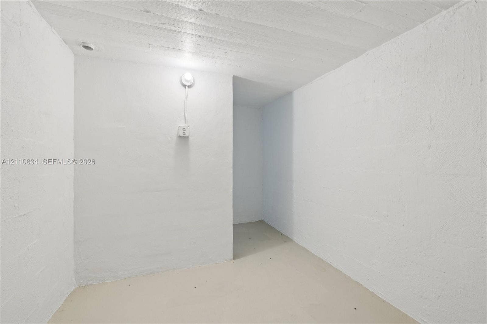 4120 SW 15th Street, Miami, FL 33142 Enclosed space featuring painted masonry walls, a concrete floor, exposed ceiling joists, and an electrical wall outlet