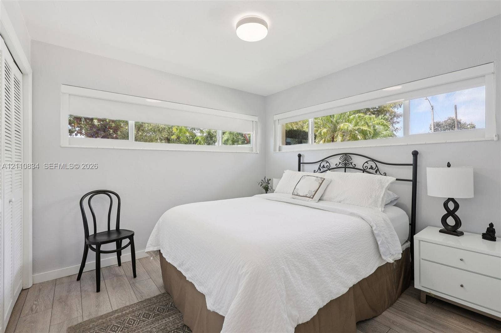4120 SW 15th Street, Miami, FL 33142 Neutral-toned interior featuring wood-finish flooring, horizontal sliding windows, and a built-in closet with bi-fold louvered doors