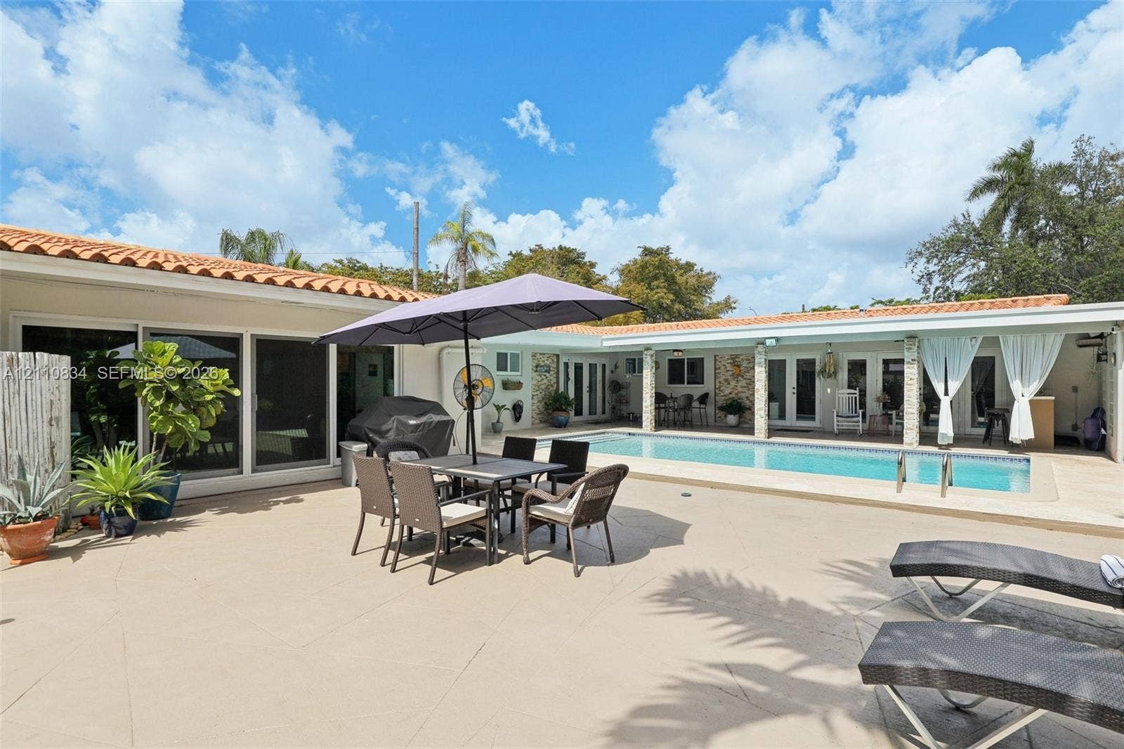 4120 SW 15th Street, Miami, FL 33142 Extensive paved patio featuring an in-ground swimming pool, clay tile roof, and covered outdoor area with stone column supports
