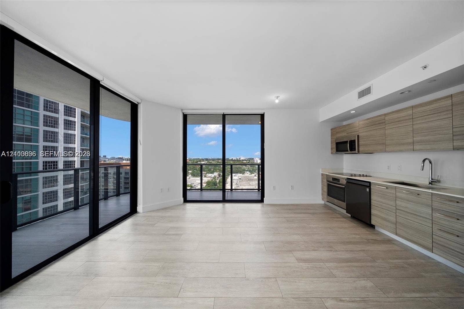 Modern kitchen featuring wood-finish cabinetry, stainless steel appliances, and integrated faucet fixtures, complemented by tile flooring and floor-to-ceiling glass panel doors