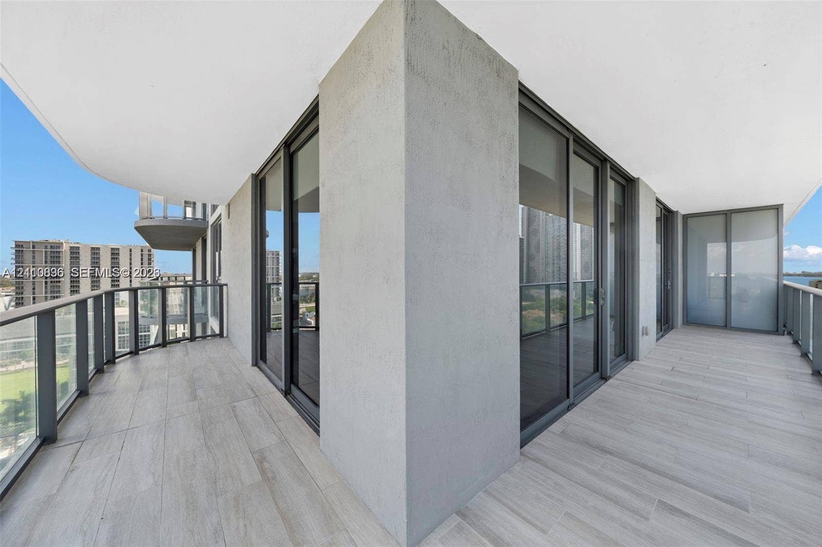 Wraparound balcony featuring tile flooring, metal railings, and floor-to-ceiling glass sliding doors