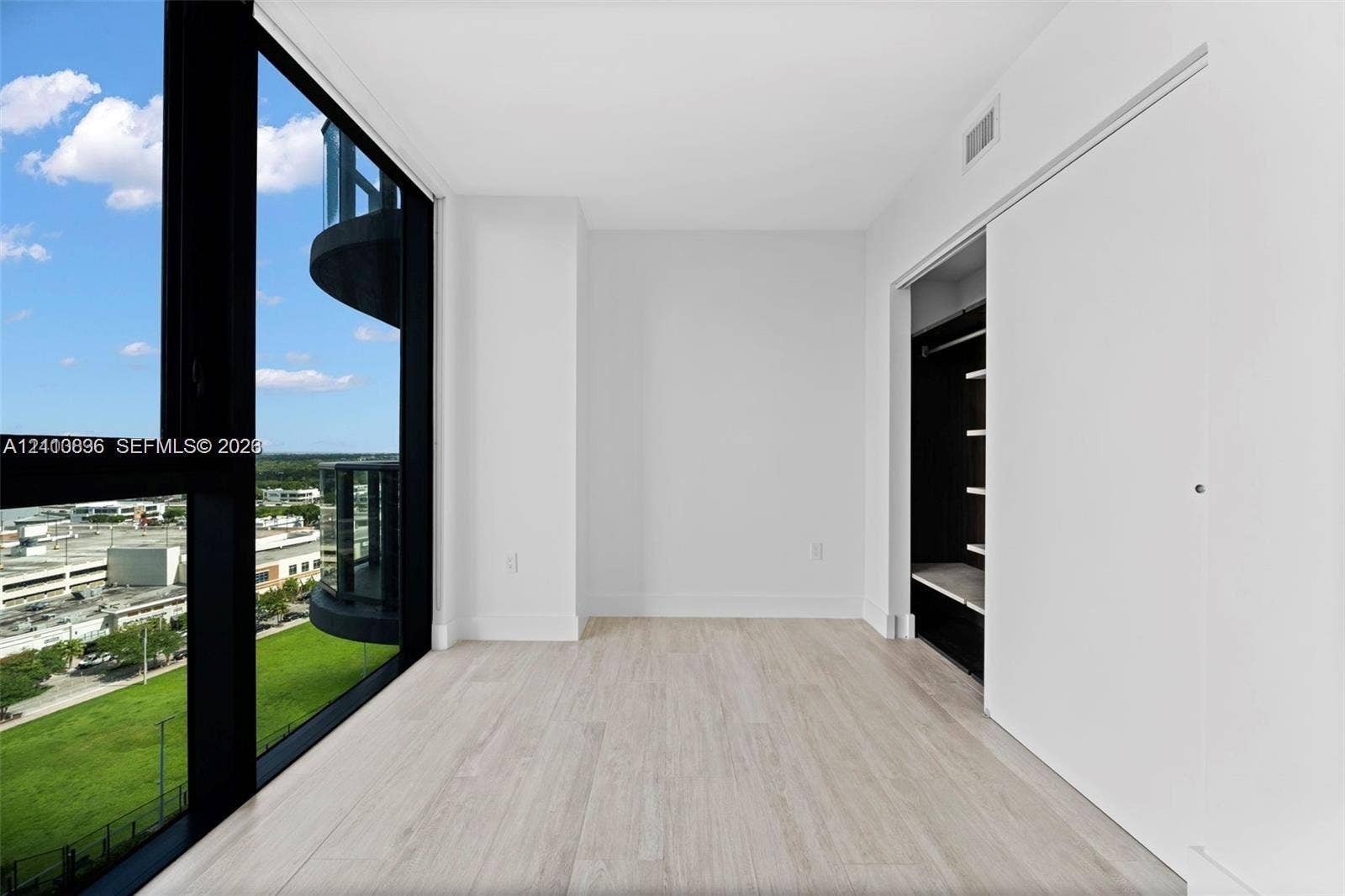 Floor-to-ceiling windows, wood-finish flooring, and a built-in closet with sliding doors