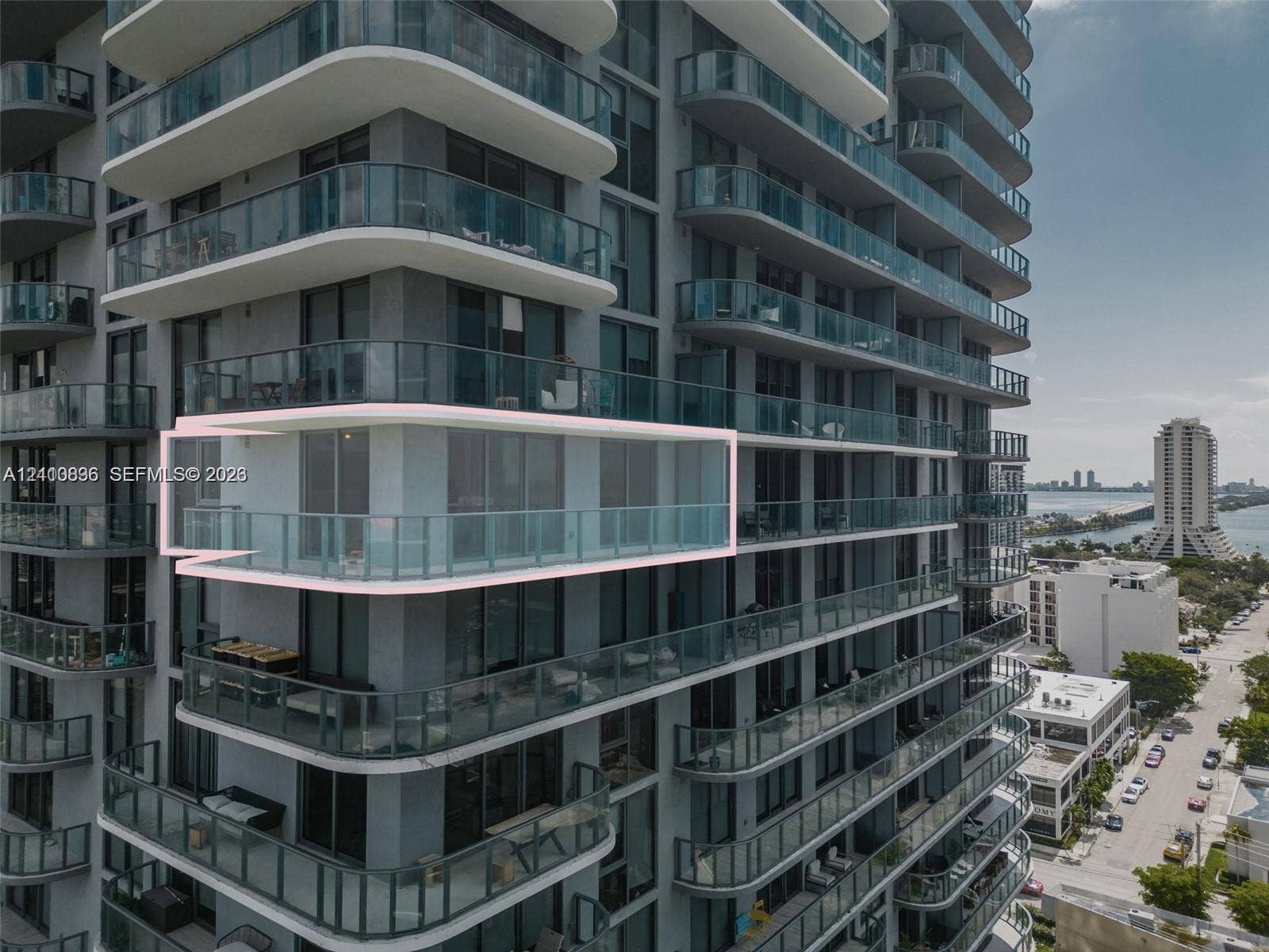 Modern high-rise residential tower featuring curved glass balconies, floor-to-ceiling windows, and streamlined white architectural trim
